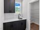 Stylish wet bar with dark cabinetry, quartz countertop, stainless steel sink, and walk-in pantry at 1849 Ballard Rd # Holly Georgian, Fuquay Varina, NC 27526