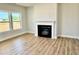 An open-concept living room features a fireplace, mantel and hearth, luxury vinyl floors, and a large window at 22 Whistling Way # Holly Farmhouse, Lillington, NC 27546