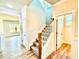 A view of the carpeted stairs with wood handrail leading to the second story, adjacent to the doorway and wood flooring at 22 Whistling Way # Holly Farmhouse, Lillington, NC 27546
