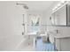 Bright bathroom featuring white tile, blue floor, tub and separate rain shower head at 230 E Park Dr, Raleigh, NC 27605