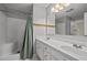 A bright bathroom with a double sink vanity, a shower with a green curtain, and vanity lighting at 3738 Lindsey Woods Rd, Hillsborough, NC 27278