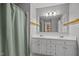 A bright bathroom with a double sink vanity, a shower with a green curtain, and vanity lighting at 3738 Lindsey Woods Rd, Hillsborough, NC 27278