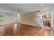 Bright living room with hardwood floors, a ceiling fan, and open access to kitchen through the stairs at 3738 Lindsey Woods Rd, Hillsborough, NC 27278