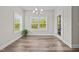 Sunlit dining room featuring wood floors, an elegant chandelier, and picturesque windows enhancing a warm atmosphere at 40 Cinnamon Teal Way, Youngsville, NC 27596
