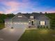Charming home featuring a three-car garage and professionally landscaped front yard at dusk at 40 Cinnamon Teal Way, Youngsville, NC 27596