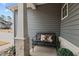 Inviting front porch with a metal bench and decorative pillows, stone accents, and neutral siding at 40 Cinnamon Teal Way, Youngsville, NC 27596