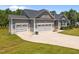 Attractive home exterior showcasing a three-car garage with decorative carriage doors and ample driveway space at 40 Cinnamon Teal Way, Youngsville, NC 27596