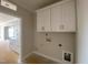 Bright laundry room with upper cabinets and utility connections at 4875 Grosbeak Ct, Mebane, NC 27302