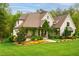 Two-story brick house featuring a well-manicured lawn, landscaped garden, and mature trees at 5040 Shakori Trl, Chapel Hill, NC 27707