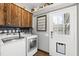 Bright laundry room featuring modern washer, dryer, custom cabinetry, and backyard access at 5819 Windham Dr, Raleigh, NC 27609