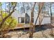 Rear exterior view of a white home featuring a wooden deck, black trim, and a backdrop of lush trees at 7 Hampton Hill Pl, Chapel Hill, NC 27517