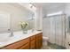 Bathroom featuring double sinks, wooden cabinetry, neutral shower curtain, and bright natural light at 708 Pitchback Mill Ct Ct, Wake Forest, NC 27587