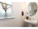 Elegant powder room with a pedestal sink, decorative mirror, and natural light from the window at 708 Pitchback Mill Ct Ct, Wake Forest, NC 27587