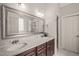 Bathroom featuring marble counters, double sinks, wood cabinets, and large mirror at 7805 Fairlake Dr, Wake Forest, NC 27587
