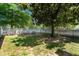 Large backyard has lush lawn and mature tree, with a white picket fence and bench at 1000 S 9Th St, Lillington, NC 27546