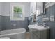 Charming bathroom with blue tiling, a window view, and a classic white sink and bathtub at 1000 S 9Th St, Lillington, NC 27546