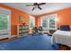 A sunlit bedroom featuring vibrant orange walls, plush blue carpet, and two large windows at 1000 S 9Th St, Lillington, NC 27546