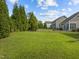 Fully fenced backyard with green lawn, mature trees, and patio seating area at 1021 Traditions Meadow Dr, Wake Forest, NC 27587