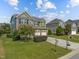 Green two story home with brick and siding exterior on a manicured lawn in residential neighborhood at 1021 Traditions Meadow Dr, Wake Forest, NC 27587