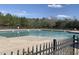 Large community pool surrounded by a black metal fence with wooded area in background under clear blue sky at 1208 Shining Water Ln, Creedmoor, NC 27522