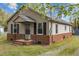 Inviting single-story home showcasing a brick foundation, neutral siding, a covered porch, and tidy landscaping at 128 Warren Ave, Oxford, NC 27565