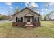 Charming single-story home with siding, brick foundation and black shutters under a cloudy blue sky at 128 Warren Ave, Oxford, NC 27565
