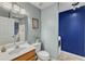 Bathroom featuring a sink, toilet, mirror, vanity lighting, and blue accent wall with a washer/dryer at 131 Dove Cottage Ln, Cary, NC 27519