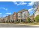 A row of brick and siding townhouses with manicured landscaping sits under a blue sky with scattered clouds at 131 Dove Cottage Ln, Cary, NC 27519