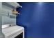 Bright laundry area features a white washer and dryer, wire shelving, and vibrant blue accent wall at 131 Dove Cottage Ln, Cary, NC 27519