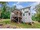 Back exterior of home featuring a patio and multiple windows, surrounded by trees and a green lawn at 1354 Red Bud Ct, Wake Forest, NC 27587