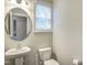 Simple half bathroom featuring a pedestal sink, toilet, and a window providing natural light at 1354 Red Bud Ct, Wake Forest, NC 27587