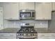 The kitchen features a stainless steel gas range, built-in microwave, and granite countertops at 1354 Red Bud Ct, Wake Forest, NC 27587