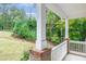 View from the covered porch with white columns and railings, overlooking the serene, wooded surroundings at 1354 Red Bud Ct, Wake Forest, NC 27587