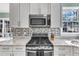Close up of modern gas range and granite counters with mosaic tile backsplash in white kitchen at 14 Wedgewood Pl, Clayton, NC 27527