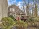 Backyard view of a gray home with a wooden deck, trees, and bushes at 1710 Falls Church Rd, Raleigh, NC 27609