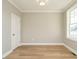 Empty room featuring hardwood floors, base trim, a light fixture, a window and a white door at 1800 Bright Lantern Way, Wendell, NC 27591