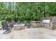 Backyard patio boasts an outdoor kitchen, built-in grill, and stone firepit lounge area at 1801 Oatlands Ct, Wake Forest, NC 27587