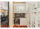 Elegant wet bar with glass cabinets, granite countertop, and built-in wine fridge at 1801 Oatlands Ct, Wake Forest, NC 27587