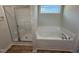 A bathroom showcasing a shower, bathtub, and a large window for natural light at 181 Tulipfield Way, Benson, NC 27504
