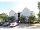 Exterior view of a multi-story building with parking spaces and flowering trees at 2520 Friedland # 202, Raleigh, NC 27617