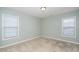 A bedroom with light blue walls, plush carpet, and two windows at 378 Oak Alley Trl, Clayton, NC 27527