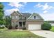Attractive brick home boasting a two-car garage, covered porch, and complemented by lush green lawn and mature tree at 378 Oak Alley Trl, Clayton, NC 27527