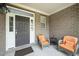 Inviting front porch with neutral brick and concrete flooring featuring comfortable wicker seating with orange cushions at 378 Oak Alley Trl, Clayton, NC 27527