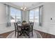 Bright dining room boasts modern chandelier, wood floors, many windows, and decorative blue and white curtains at 40 Thunder Valley Ct, Lillington, NC 27546