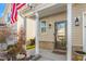Close up of the front porch showing decorative plants, a glass storm door, and an American flag at 4052 Dunkirk Dr, Burlington, NC 27215