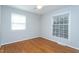 Bedroom featuring hardwood floors, neutral paint, and two windows providing natural light and outdoor views at 513 Princeton St, Raleigh, NC 27609