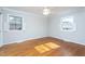 This empty bedroom has two windows, a ceiling fan, and hardwood flooring at 513 Princeton St, Raleigh, NC 27609