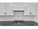Close-up view of a gas cooktop on a gray countertop with white backsplash and cabinets at 525 Marion Hills Way, Knightdale, NC 27545