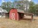 Red barn features white trim, offering practical space with attached storage at 582 Pollyanna Rd, Henderson, NC 27537