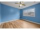 Bright blue bedroom with wood-look flooring, a ceiling fan, and a window allowing natural light at 582 Pollyanna Rd, Henderson, NC 27537